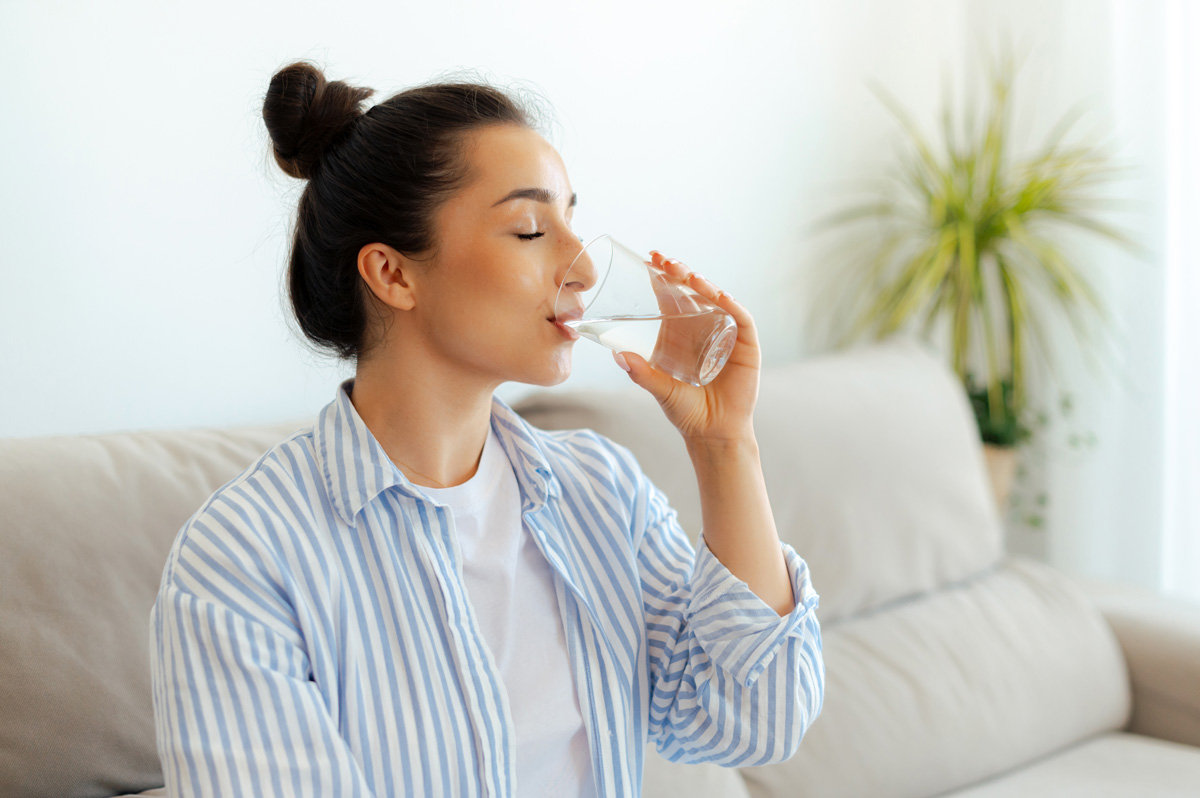 Persona che beve acqua pura da un bicchiere di vetro